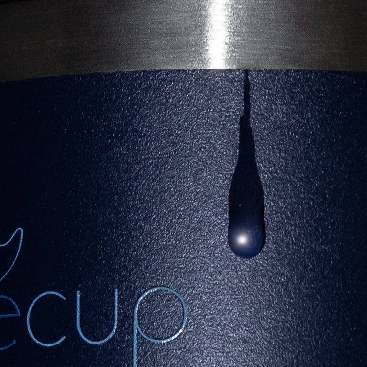 Close-up of water droplet on Whalecup tumbler with matte navy surface and stainless steel rim