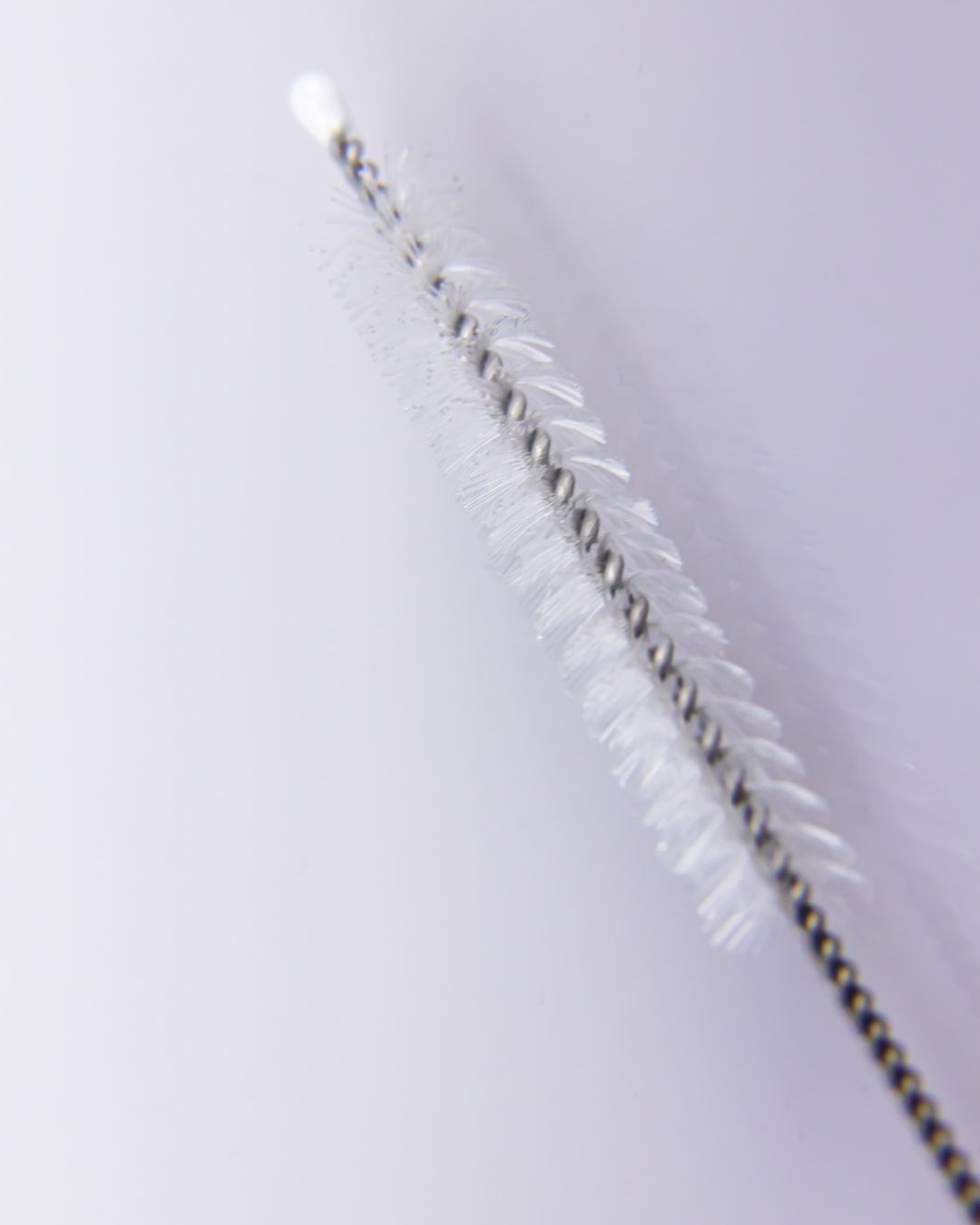 Close-up of a straw cleaning brush showing soft white bristles and twisted stainless steel wire for effective deep cleaning.