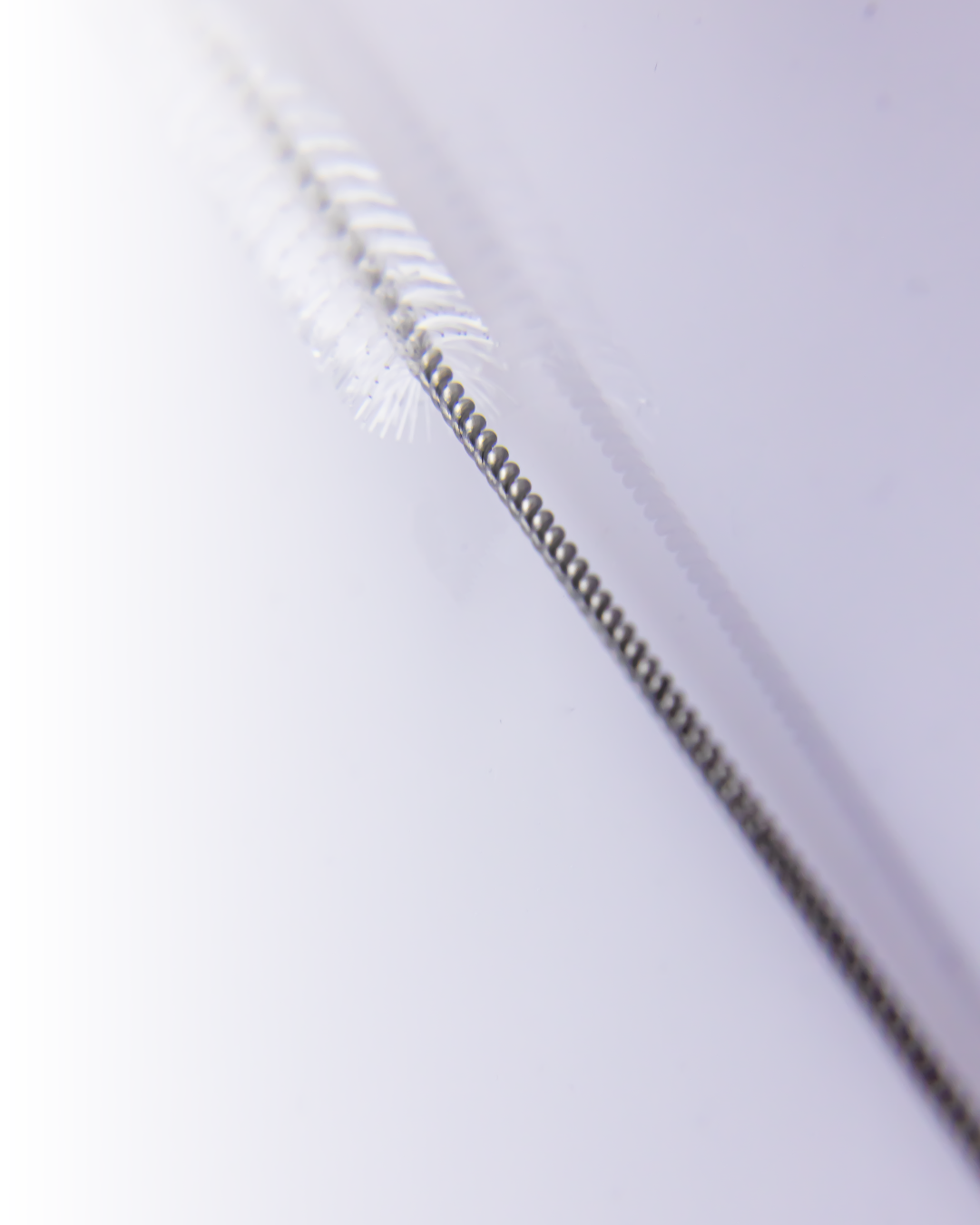 Macro view of the twisted wire handle and fine bristles of a straw cleaning brush, showing durable and precise construction.