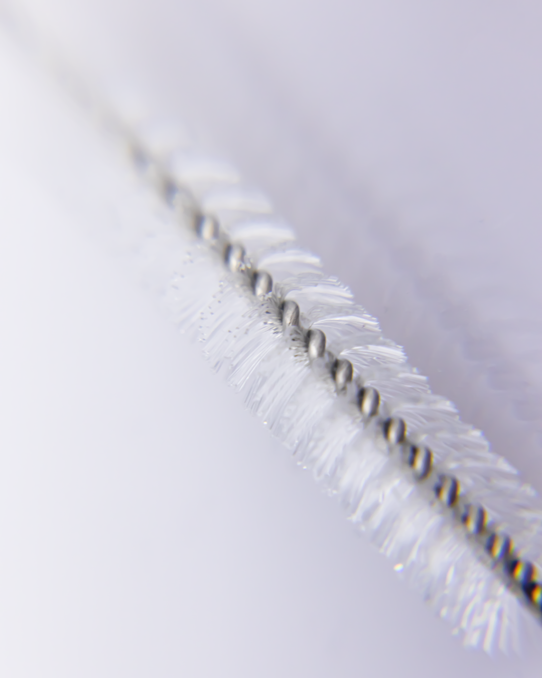 Extreme close-up of straw brush bristles and twisted wire, highlighting the fine detail and precision of the cleaning tool.