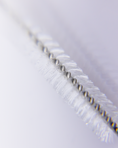 Extreme close-up of straw brush bristles and twisted wire, highlighting the fine detail and precision of the cleaning tool.